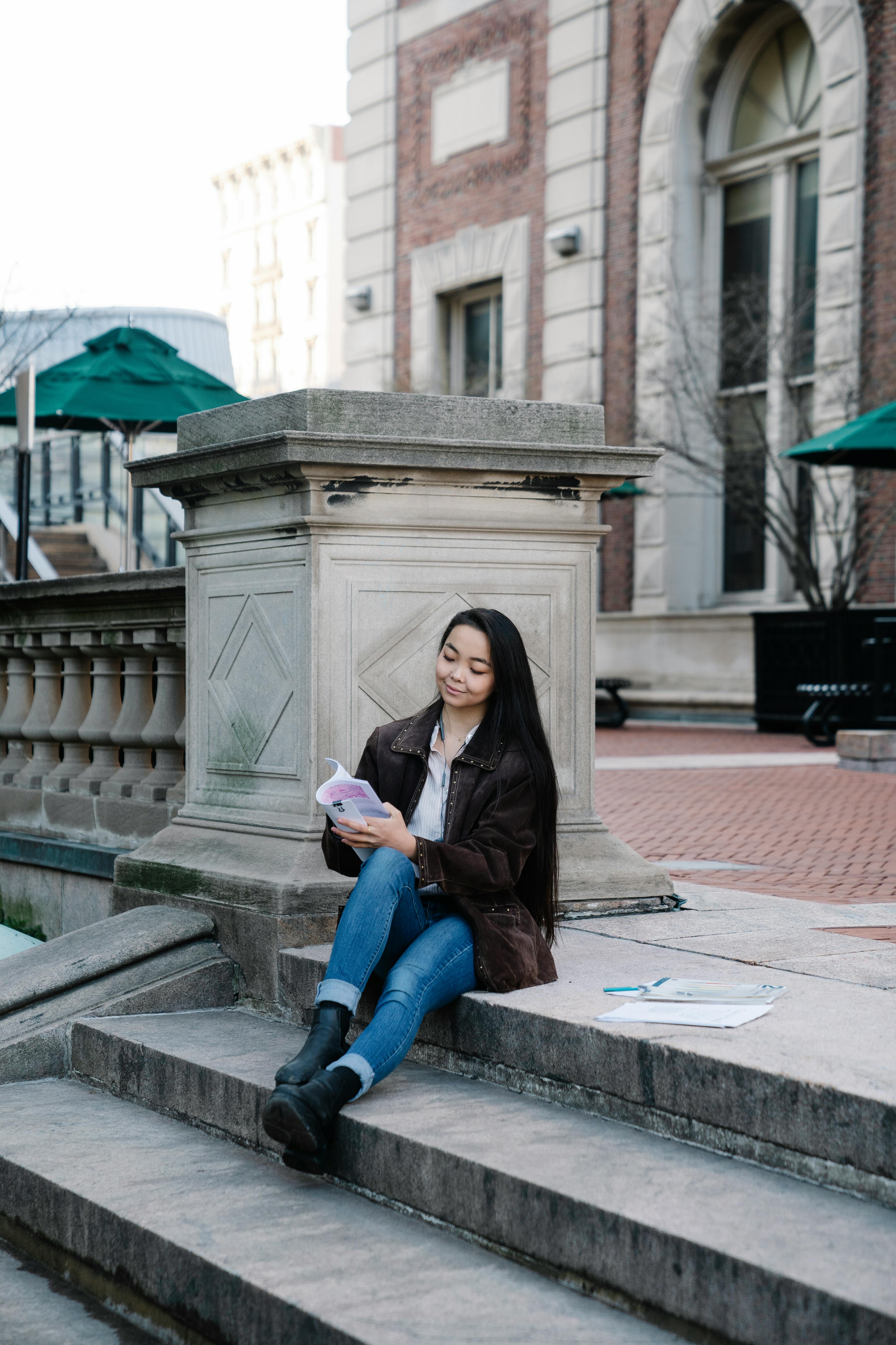 a woman studying while sitting on a concrete staircase