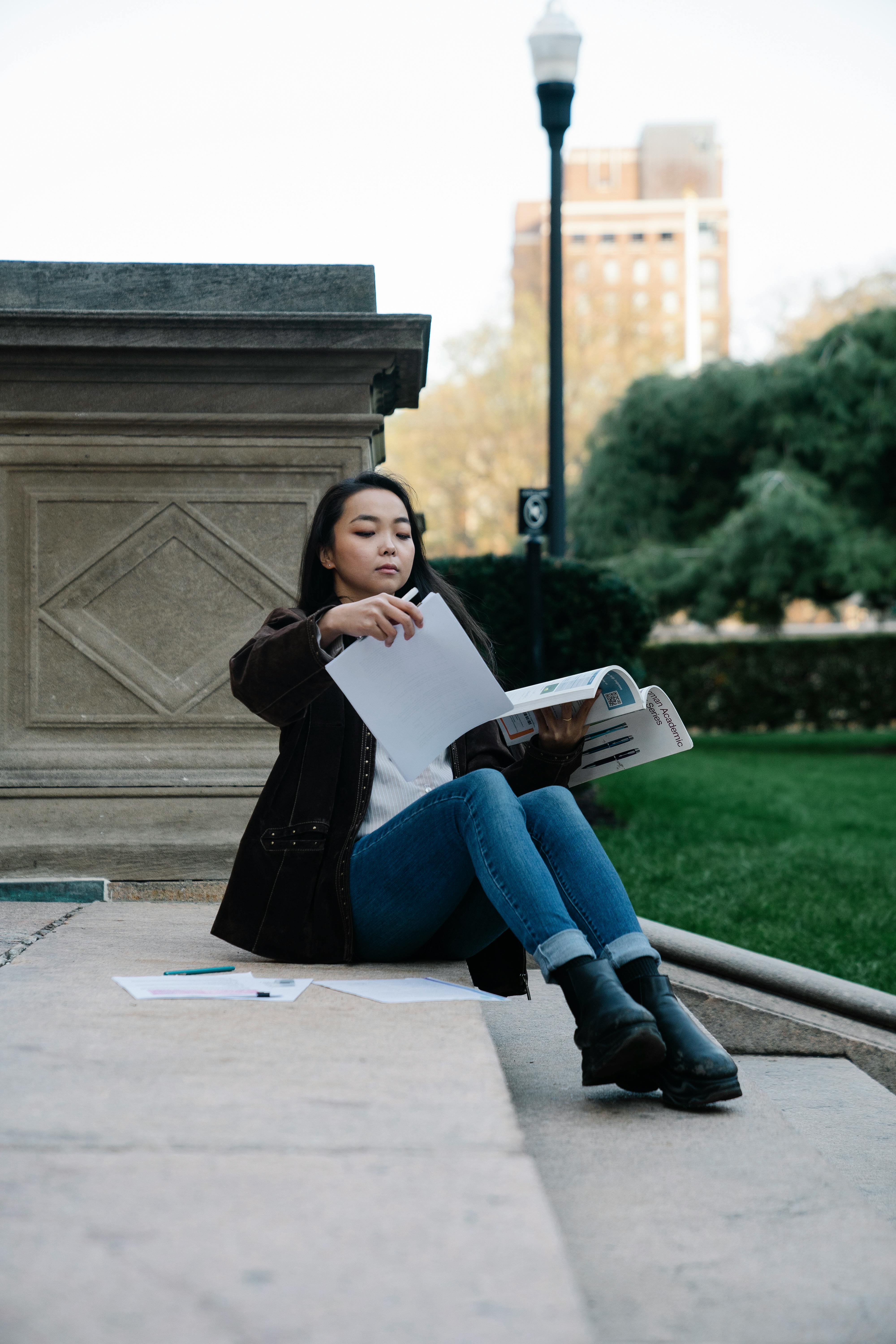 a woman studying while sitting on a concrete staircase