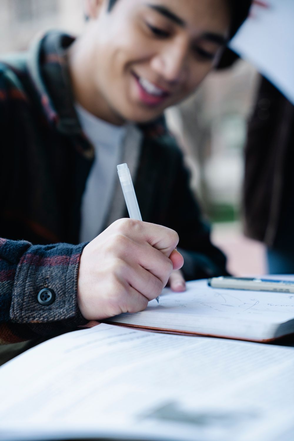 Close-Up Shot of a Man Writing on a Notebook · Free Stock Photo