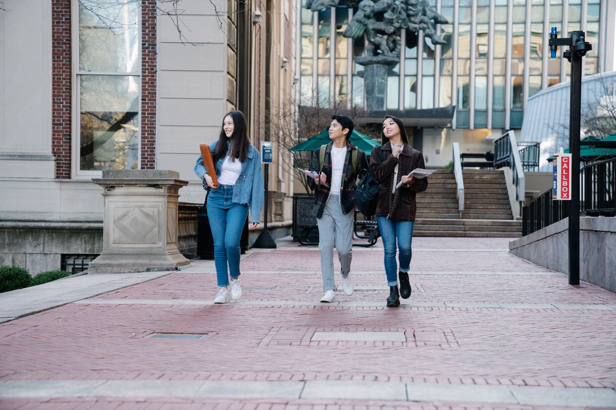College students walking and talking together on a brick plaza outside a campus building