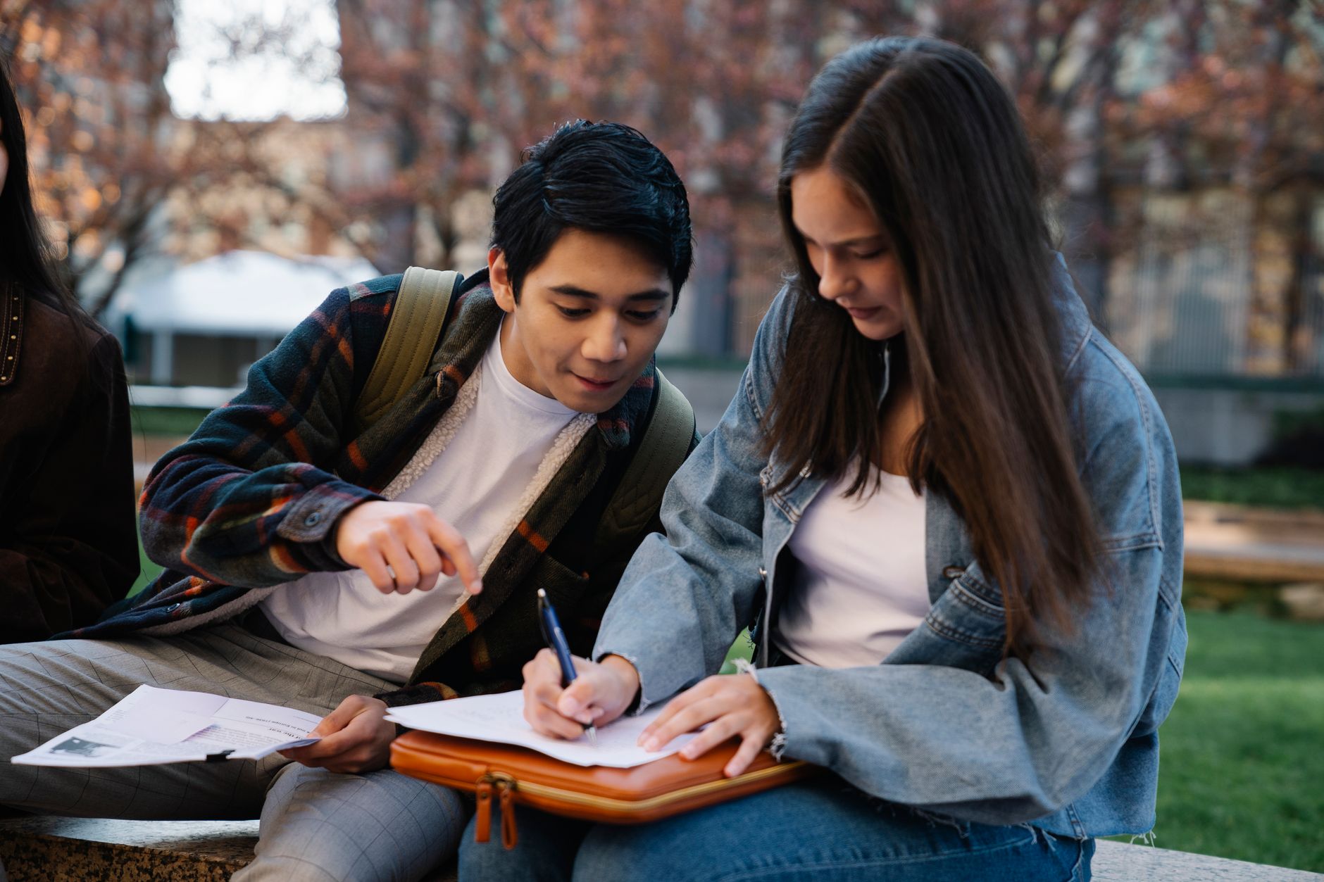 Two students reviewing scholarship documents outdoors