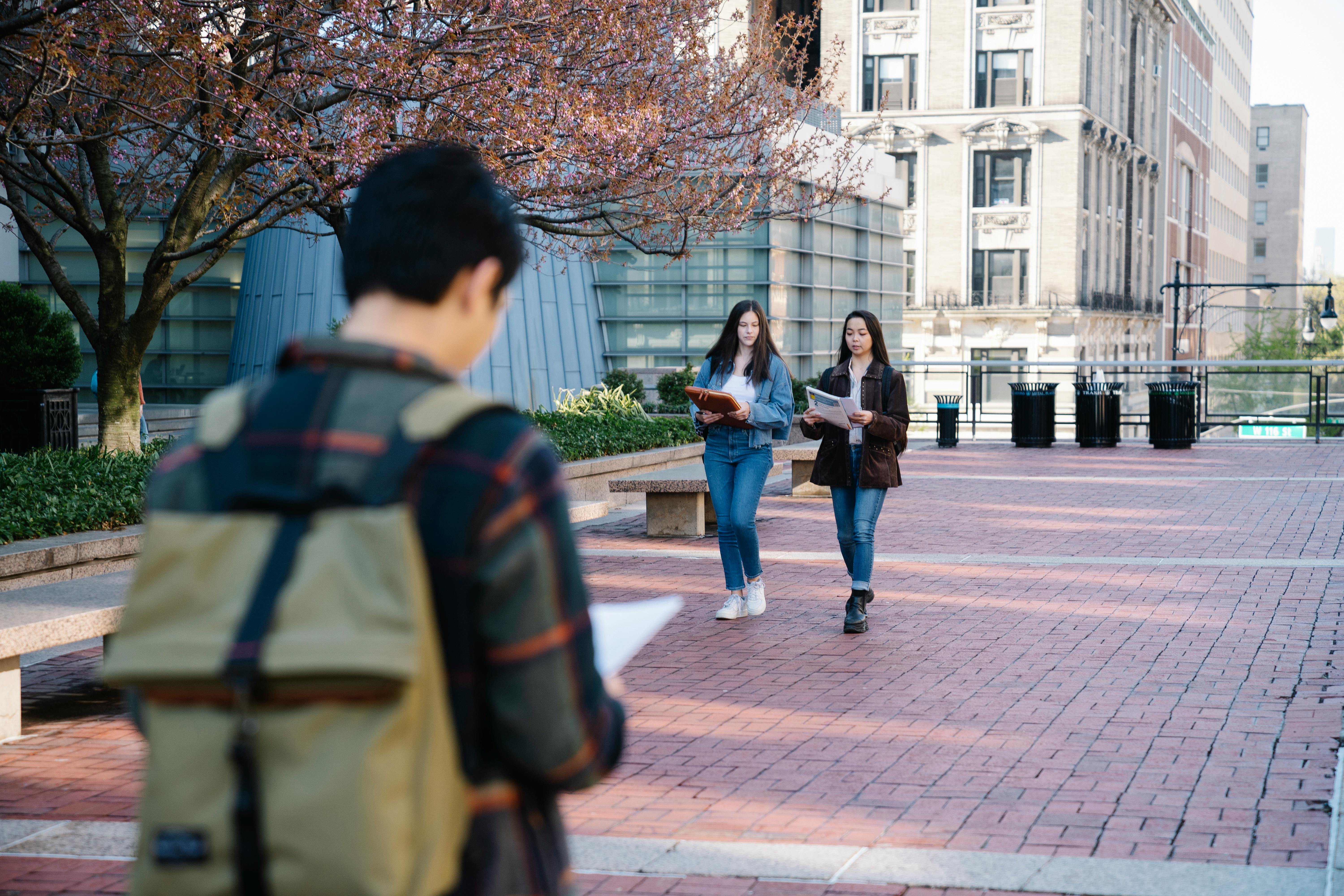 students with books walking campus street