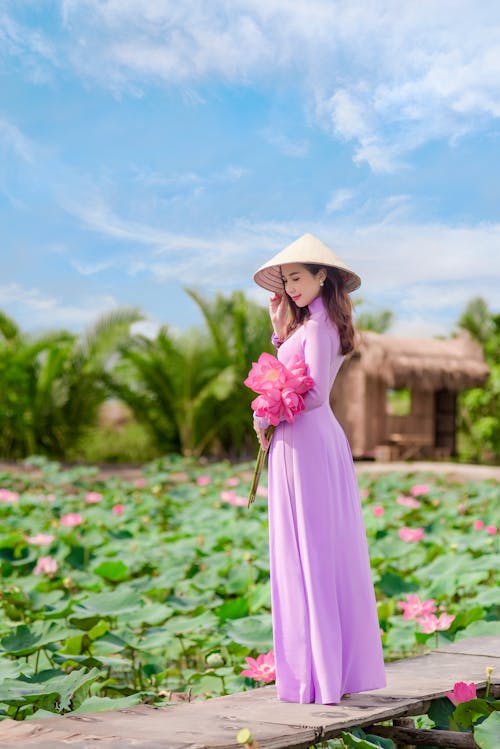 Free Photo of a Woman in a Purple Dress Touching Her Asian Conical Hat Stock Photo