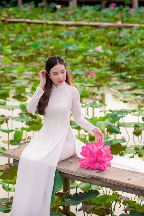 Free Photo of a Woman in a White Dress Sitting Near a Pond Stock Photo