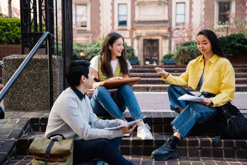 Free A group of college students sitting and discussing on university steps, engaging in lively conversation. Stock Photo
