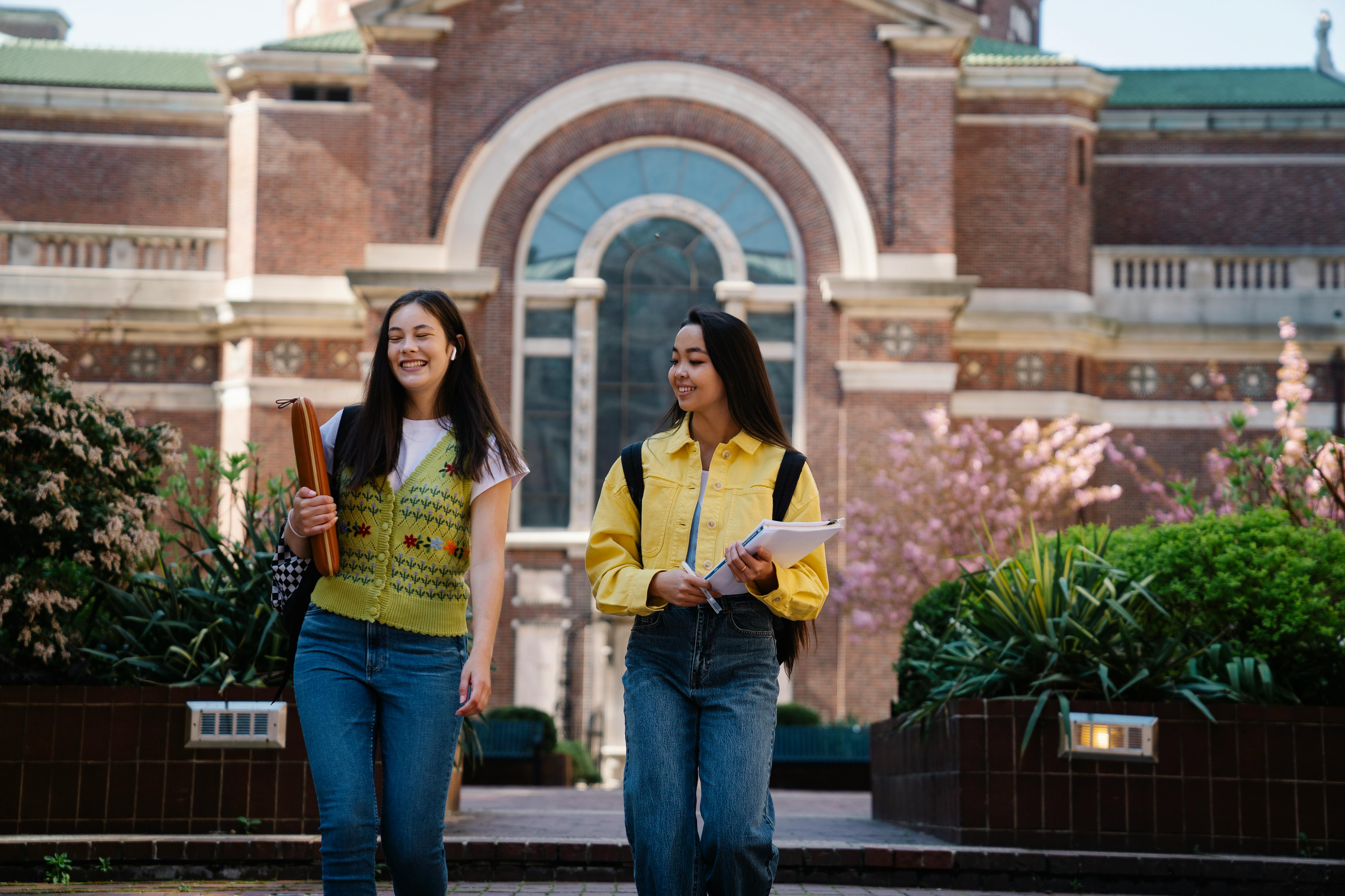 college girl walking with their notes and smiling