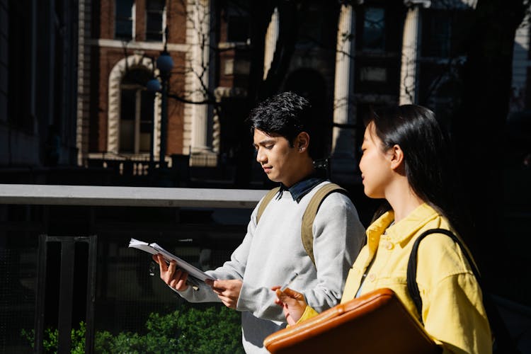 College Friends Walking And Looking At Notes 