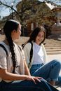 Teenage Girls Sitting on Concrete Pavement