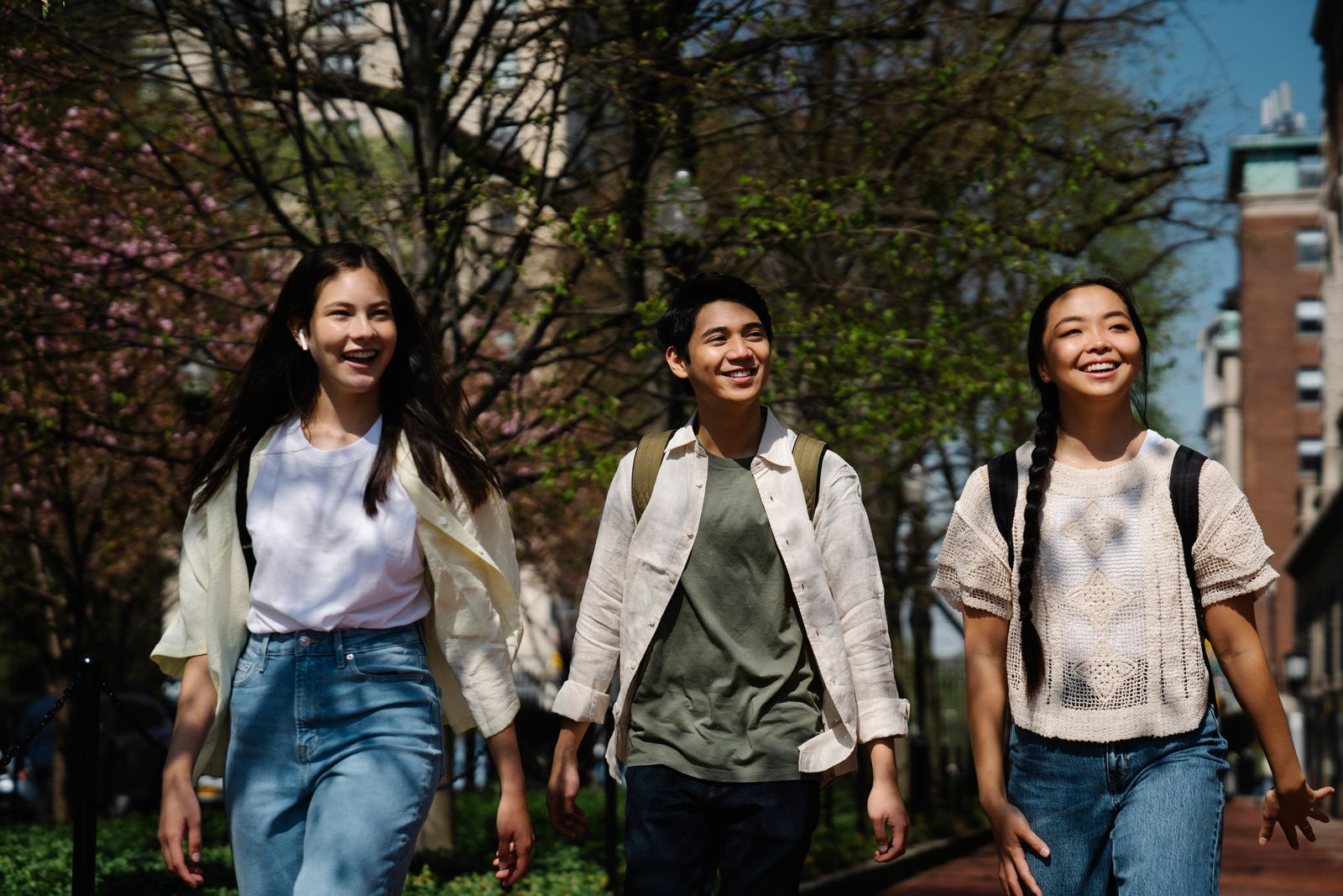 Three young friends walking together outdoors in a sunny park