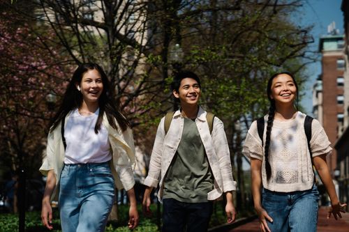 Three friends walking together outdoors on a sunny day, a relaxed setting for meeting online friends in person