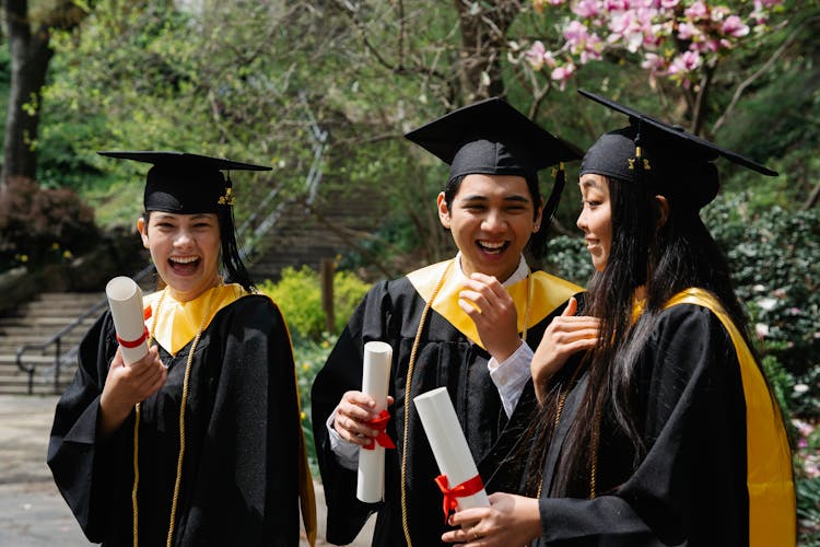 Happy Students Celebrating Graduation Holding Diplomas