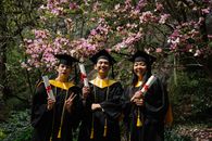 Woman in Black Academic Gown Standing Near Purple Flower Tree