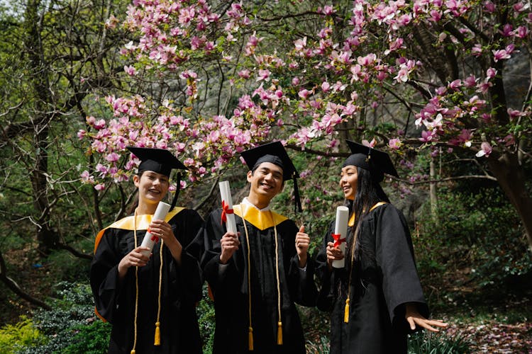 Smiling Students With Diplomas In Garden