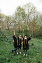People in Academic Dress Standing on Green Grass Field
