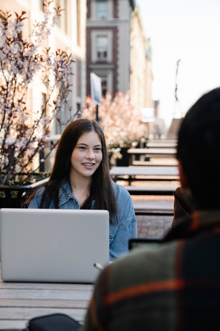 Students Sitting Outdoors Studying On Laptops