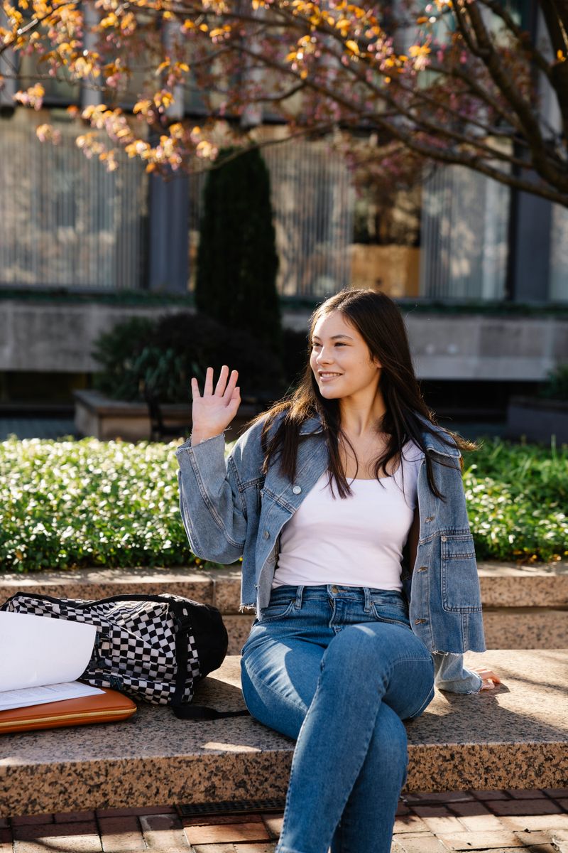 Woman in denim jacket and jeans sitting in park, relaxed weekend outfit