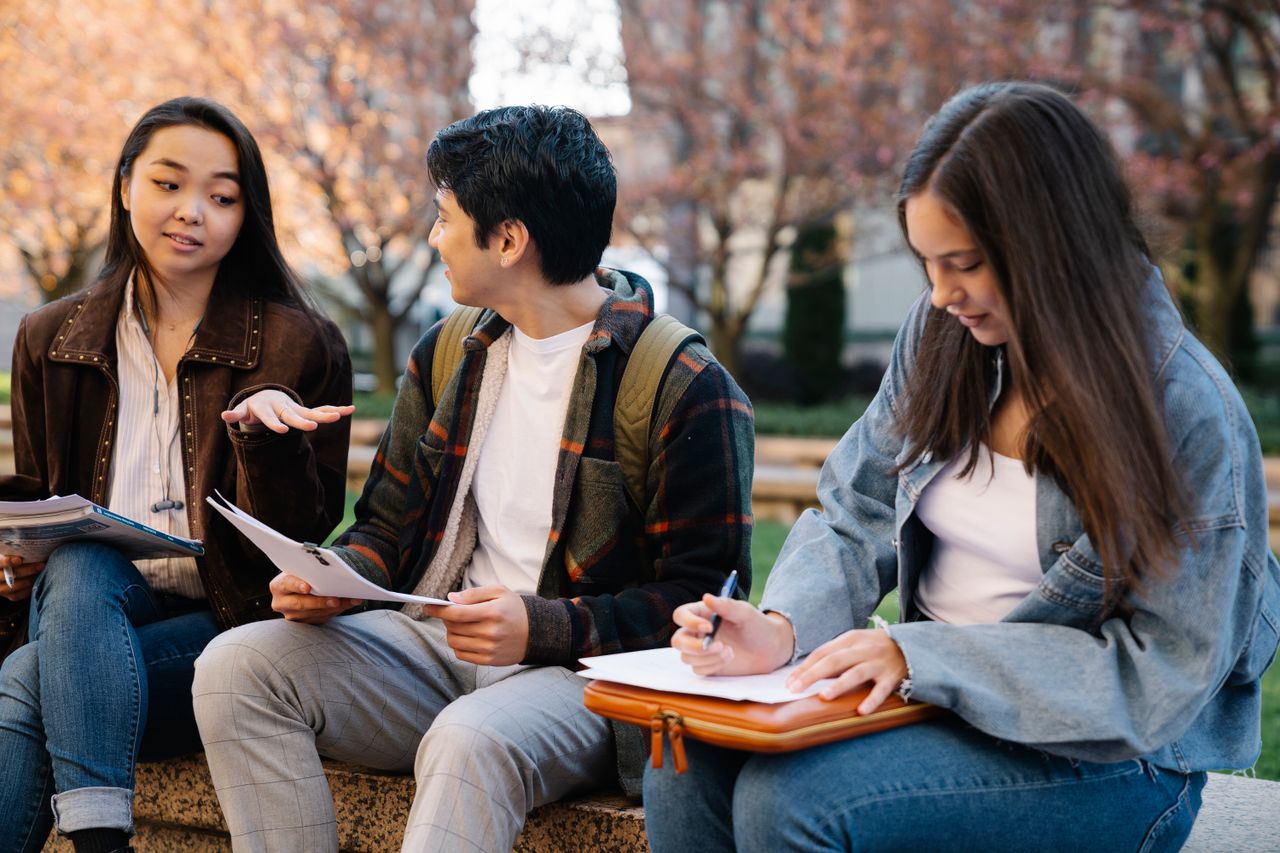 Three students sitting and studying together in a campus setting