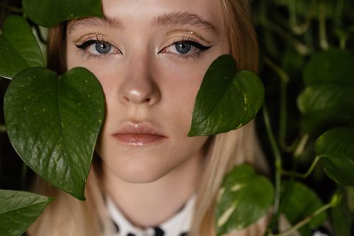 Free Close-up portrait of a woman surrounded by green leaves, showcasing natural beauty. Stock Photo