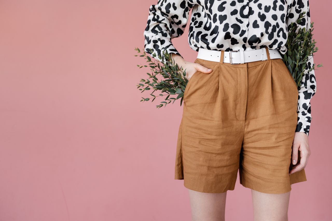 Woman wearing tailored camel linen shorts with a white belt