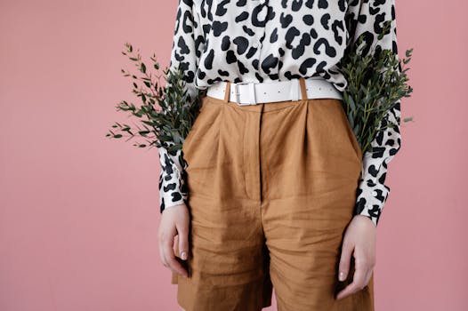 Close-up shot of a person in stylish shorts and a leopard print shirt with plants tucked in pockets.