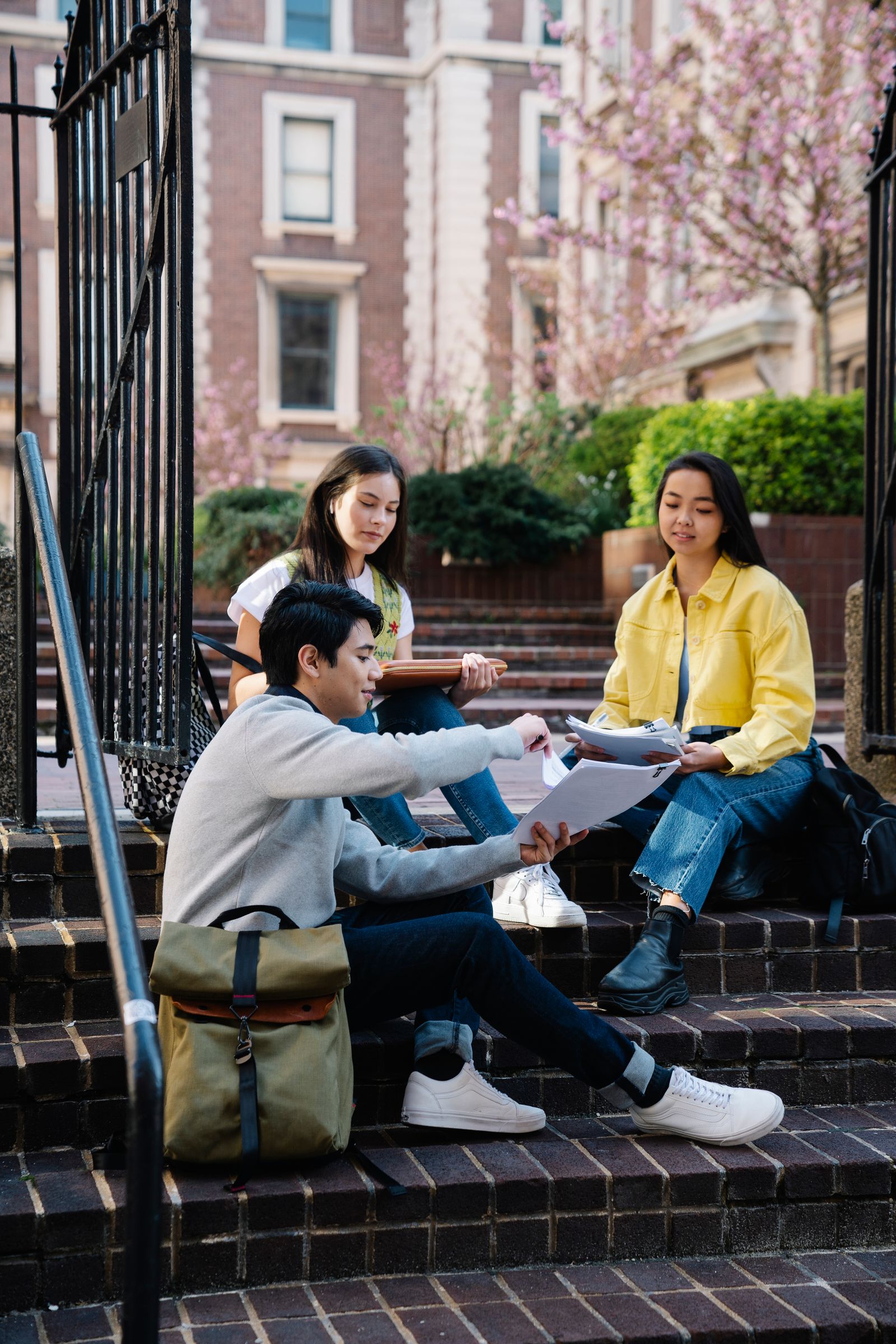 University students sitting on steps while discussing assignments.