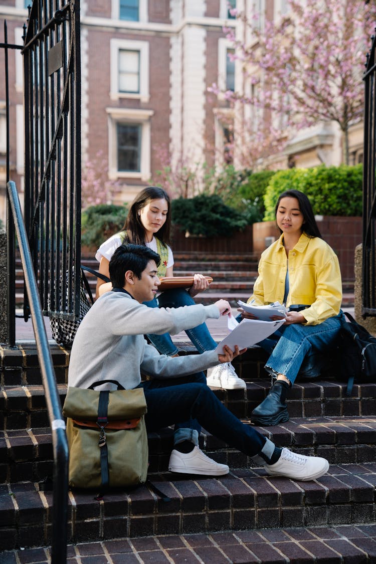 University Students Sitting On Steps And Studying