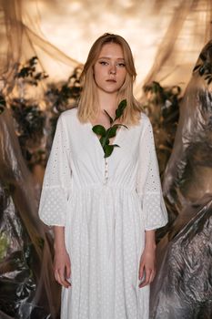 A serene woman in a white dress, surrounded by lush green foliage, embodies an organic and elegant aesthetic.