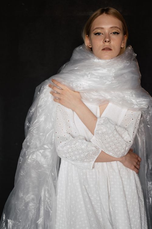 Free Dramatic portrait of a woman in white dress draped with plastic, evoking conceptual art. Stock Photo