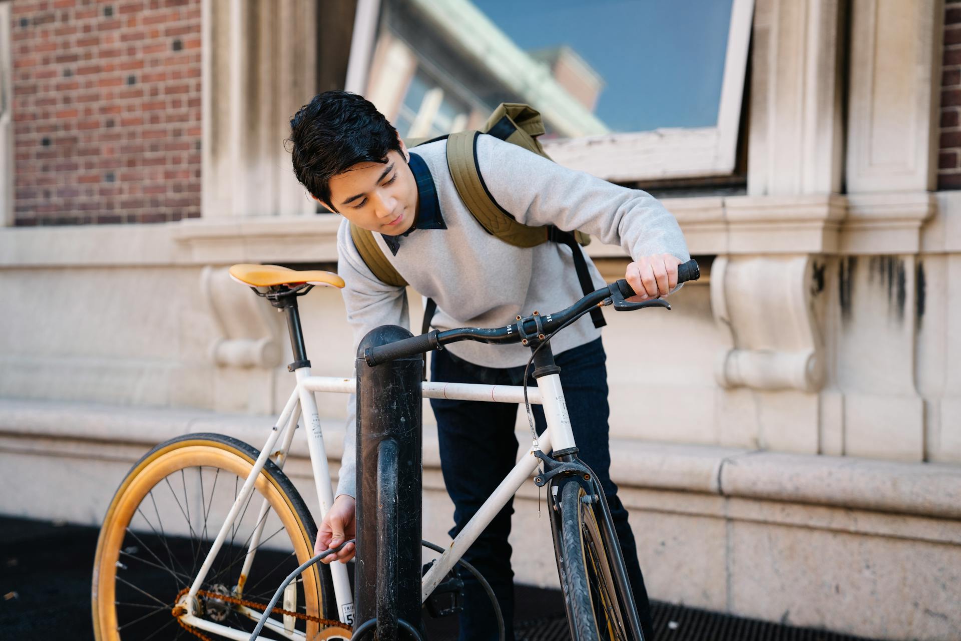 Young Man Placing His Bike Near a Post