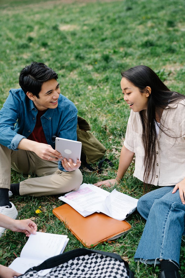 Man And Woman Sitting On Grass Field 