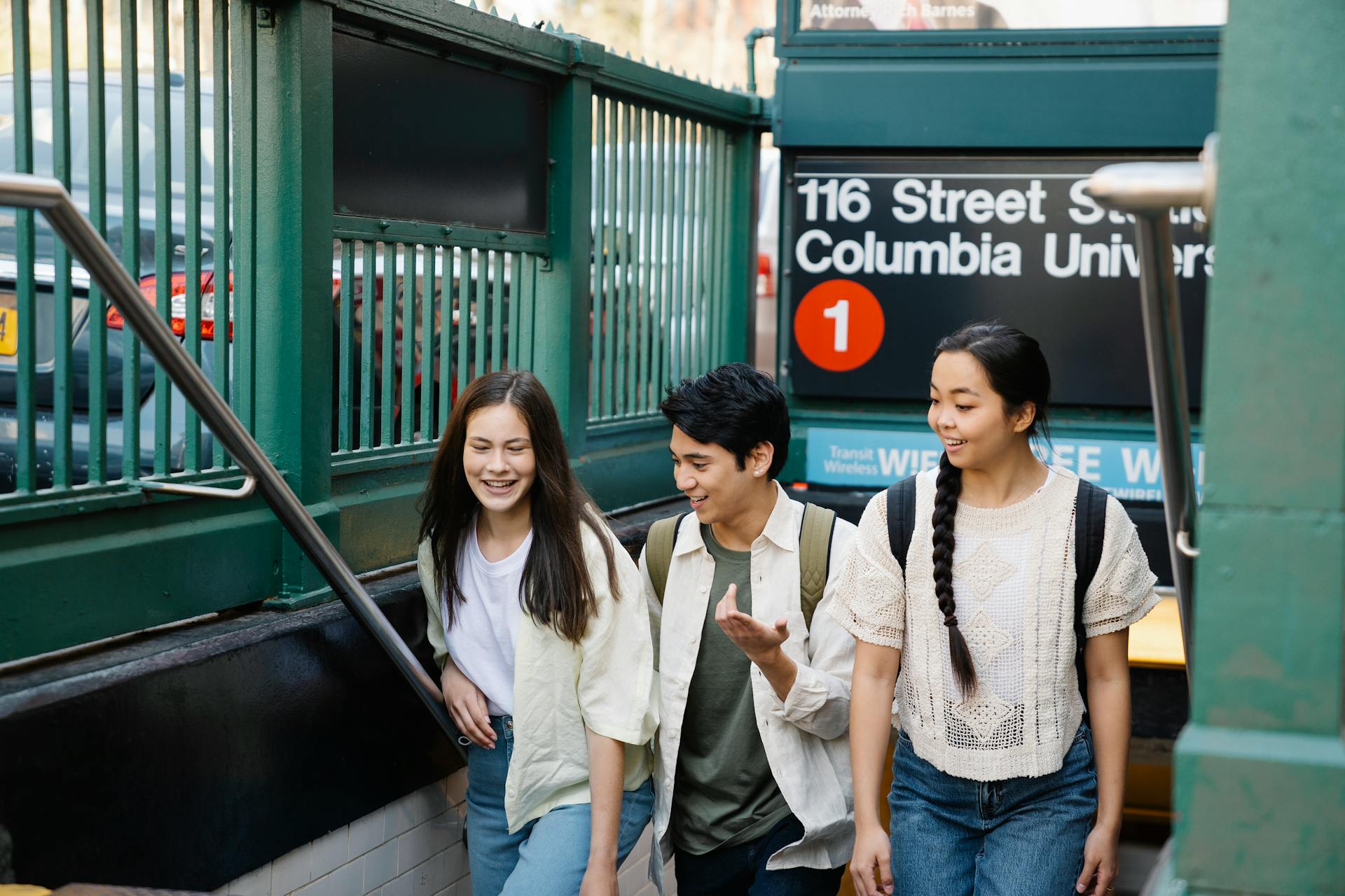 People with Backpack Waling Up on the Stairs with Street Signboard