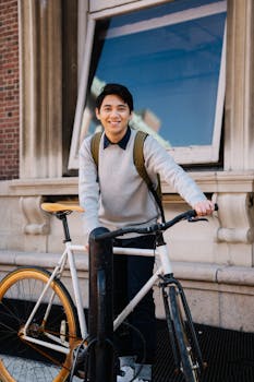Smiling young man with bicycle outdoors in urban area, showcasing lifestyle and transport.