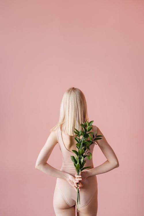 A Woman Wearing Swimwear Holding Leaves at Her Back