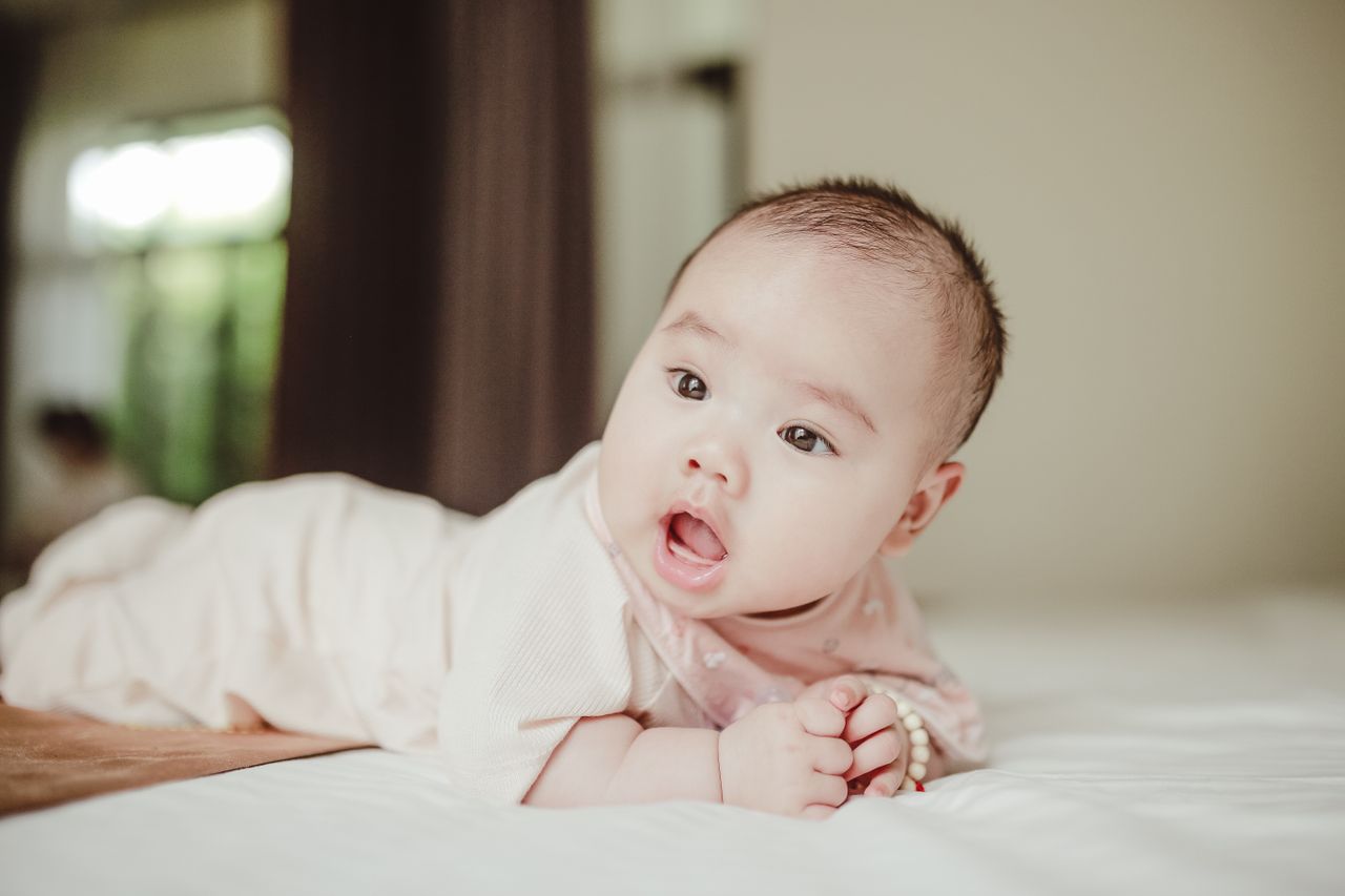 cute baby lying on bed looking curiously perfect for family and lifest