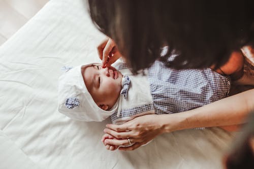 Free Crop mother stroking newborn baby on bed Stock Photo