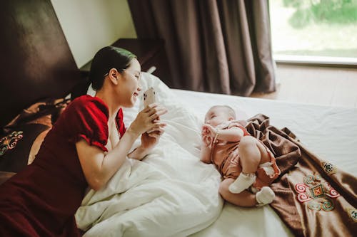 Free Mother and baby resting on bed in morning in bedroom Stock Photo