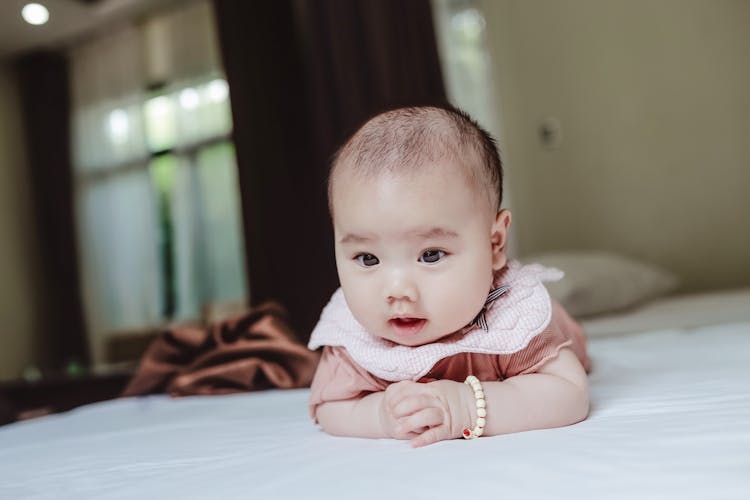 Adorable Newborn Baby Lying On Stomach On Bed