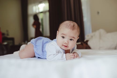 Cute baby boy lying on belly on bed