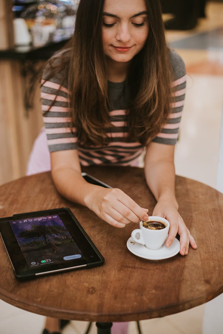 Close-Up Photo Of A Woman Stirring Her Espresso Drink