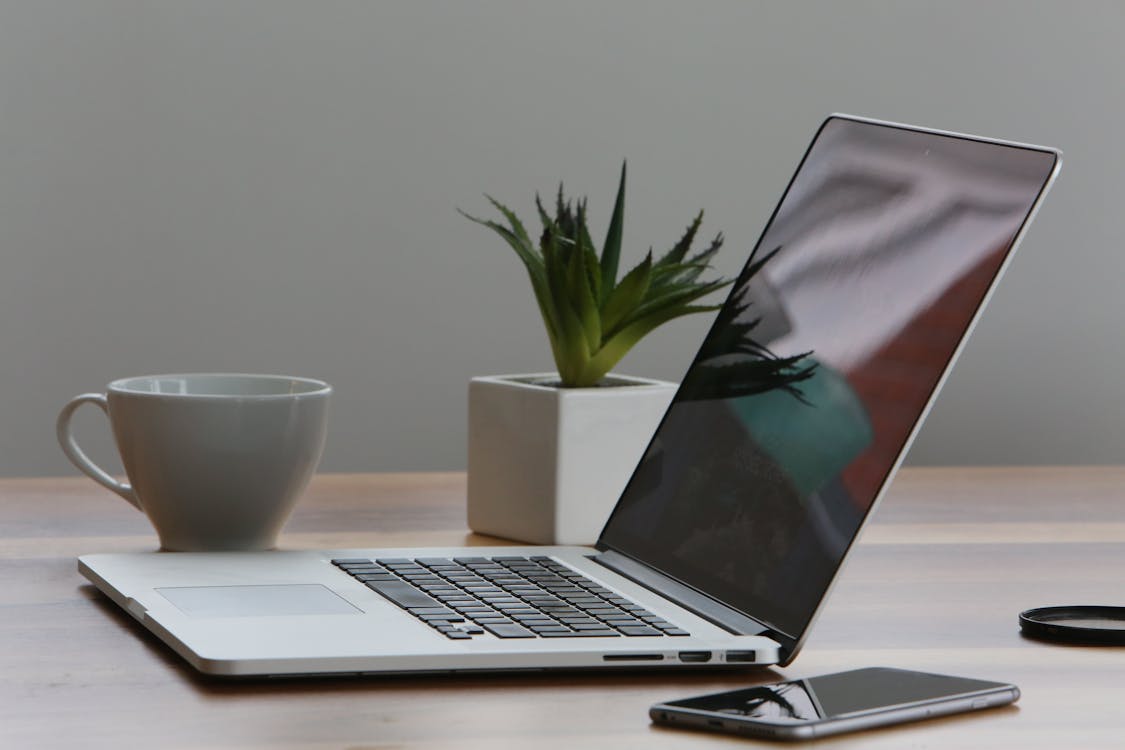 Free Silberner Laptop Und Weiße Tasse Auf Dem Tisch Stock Photo