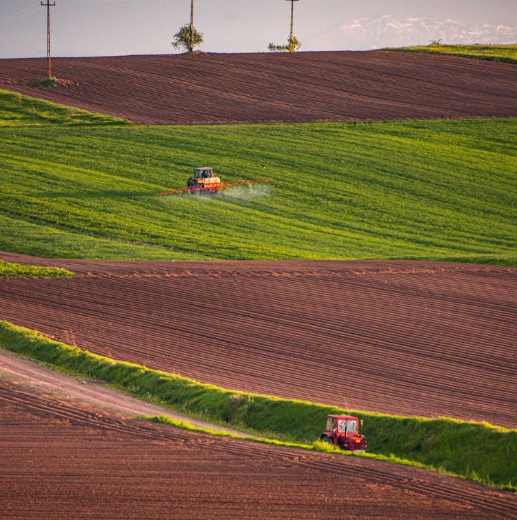 Photo Of A Tractor Spraying On Crops