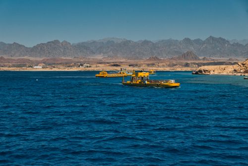 Free Yellow boats float on the vibrant blue waters of Ras Mohammed with scenic Egyptian mountains in the background. Stock Photo