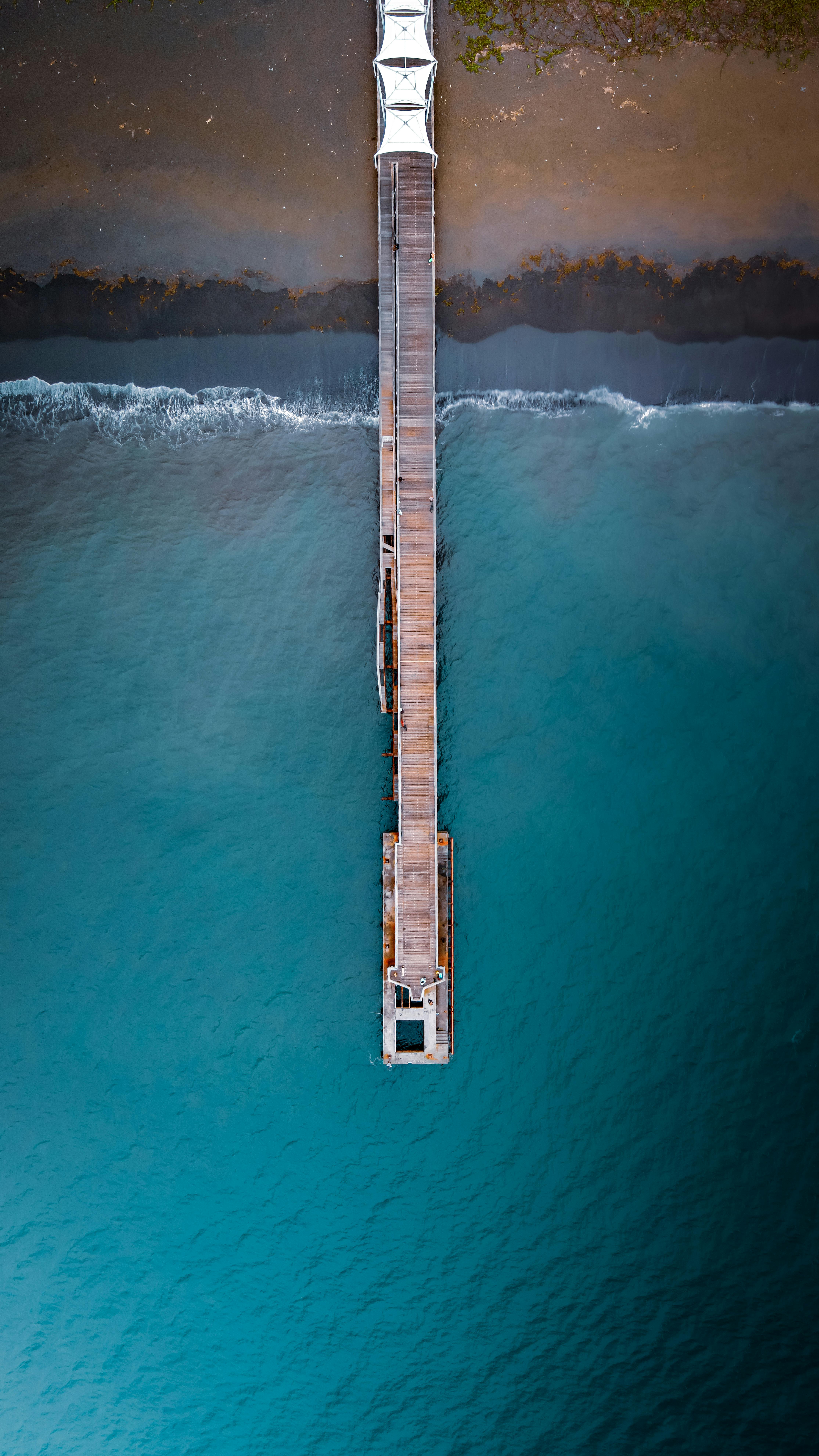 Stunning aerial shot of a pier extending into turquoise waters near the coast of Saint-Paul, Réunion.