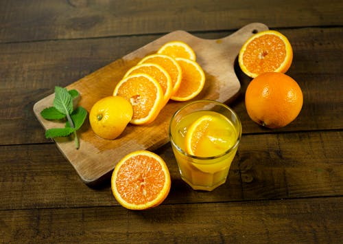 Close-Up Photo of Slices of Orange Near a Glass with Orange Juice