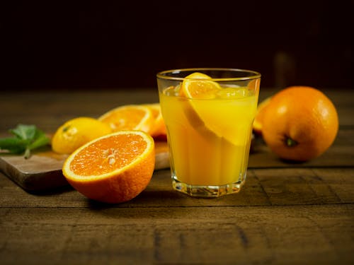 Free Selective Focus Photo of a Glass of Orange Juice Near a Sliced Orange Stock Photo
