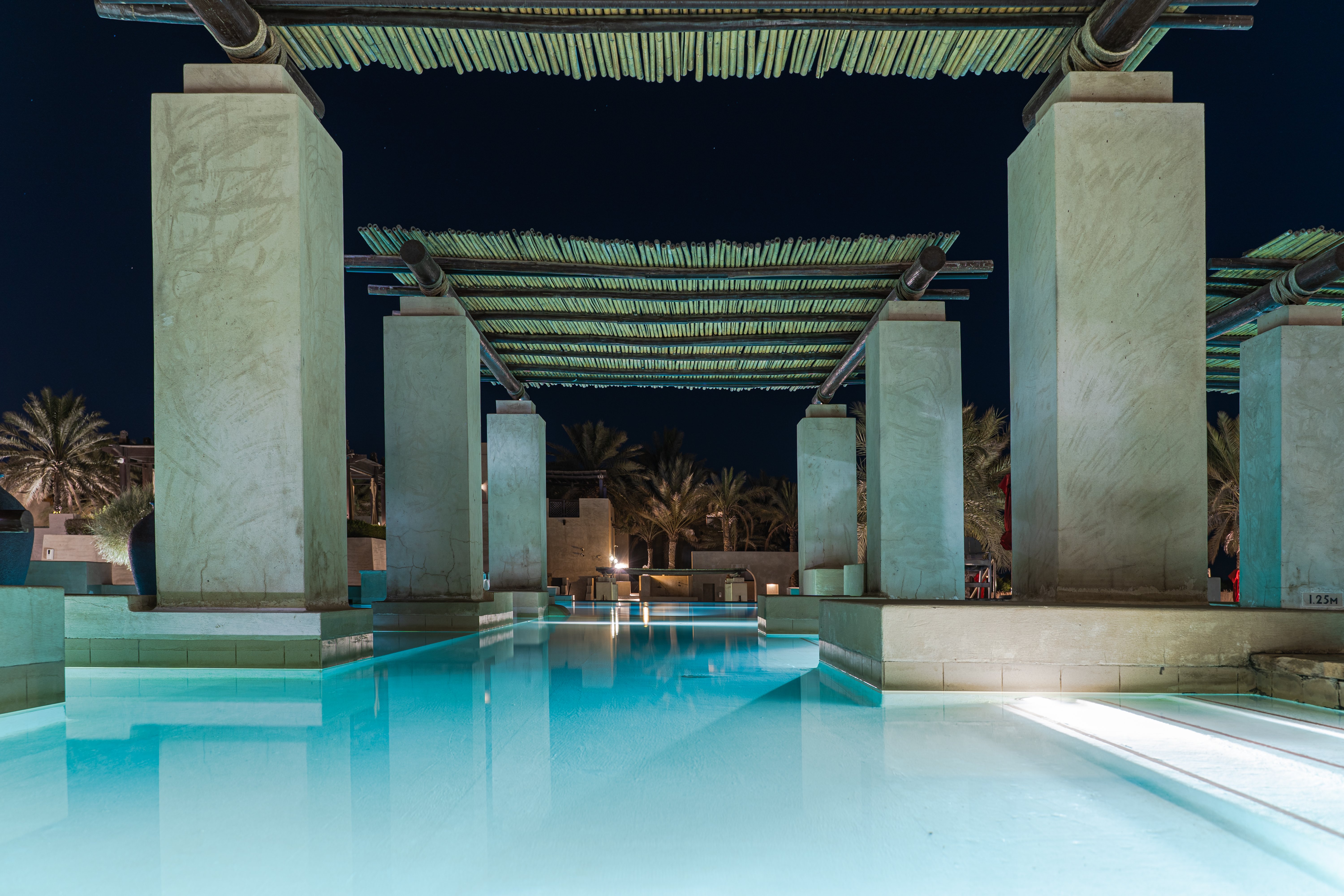 Stunning poolside view of a luxury hotel in Dubai by night, perfect for relaxation.