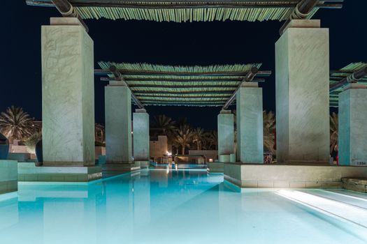 Stunning poolside view of a luxury hotel in Dubai by night, perfect for relaxation.