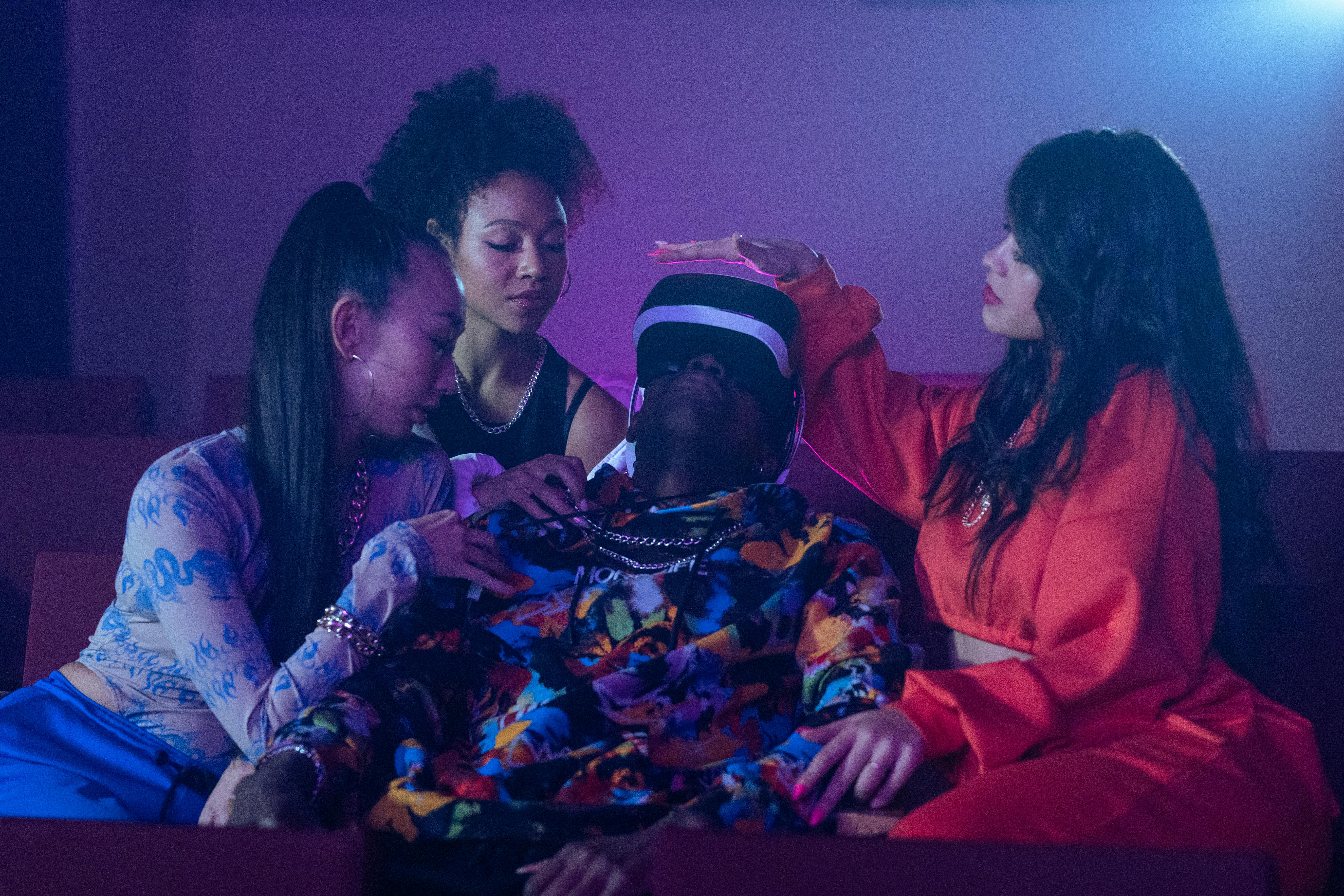 a man wearing a vr goggles surrounded by women