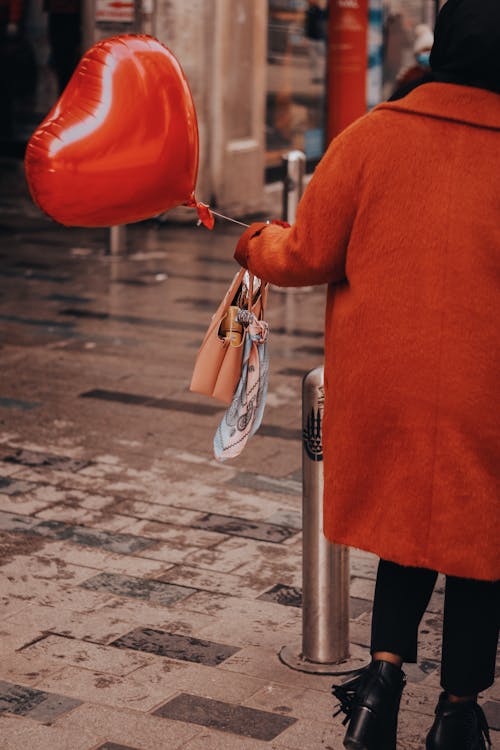 A Person Holding a Heart-shaped Red Balloon