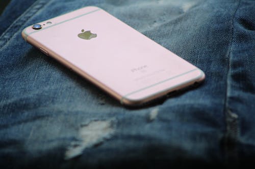 무료 블루 데님 청바지 위에 로즈 골드 아이폰 6s의 클로즈업 사진 스톡 사진